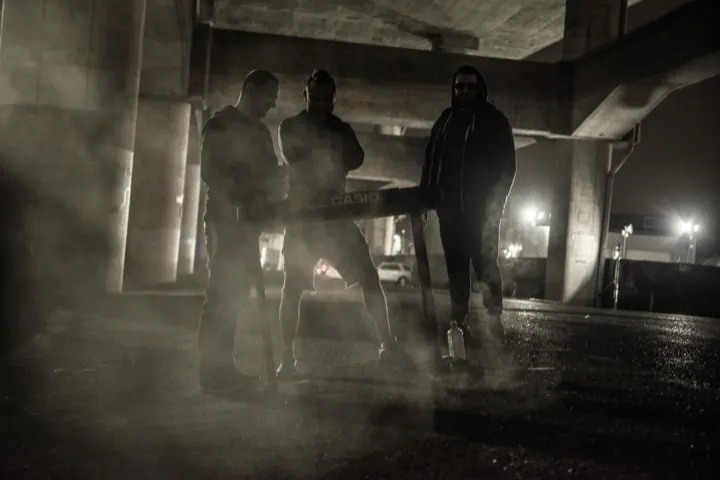 Black and white photo of the band walking through fog beneath an overpass